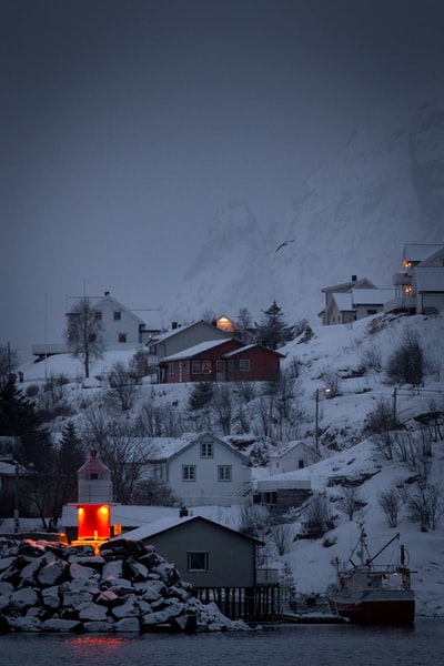 橘色灯光下的塔楼笼罩着白雪覆盖的村庄